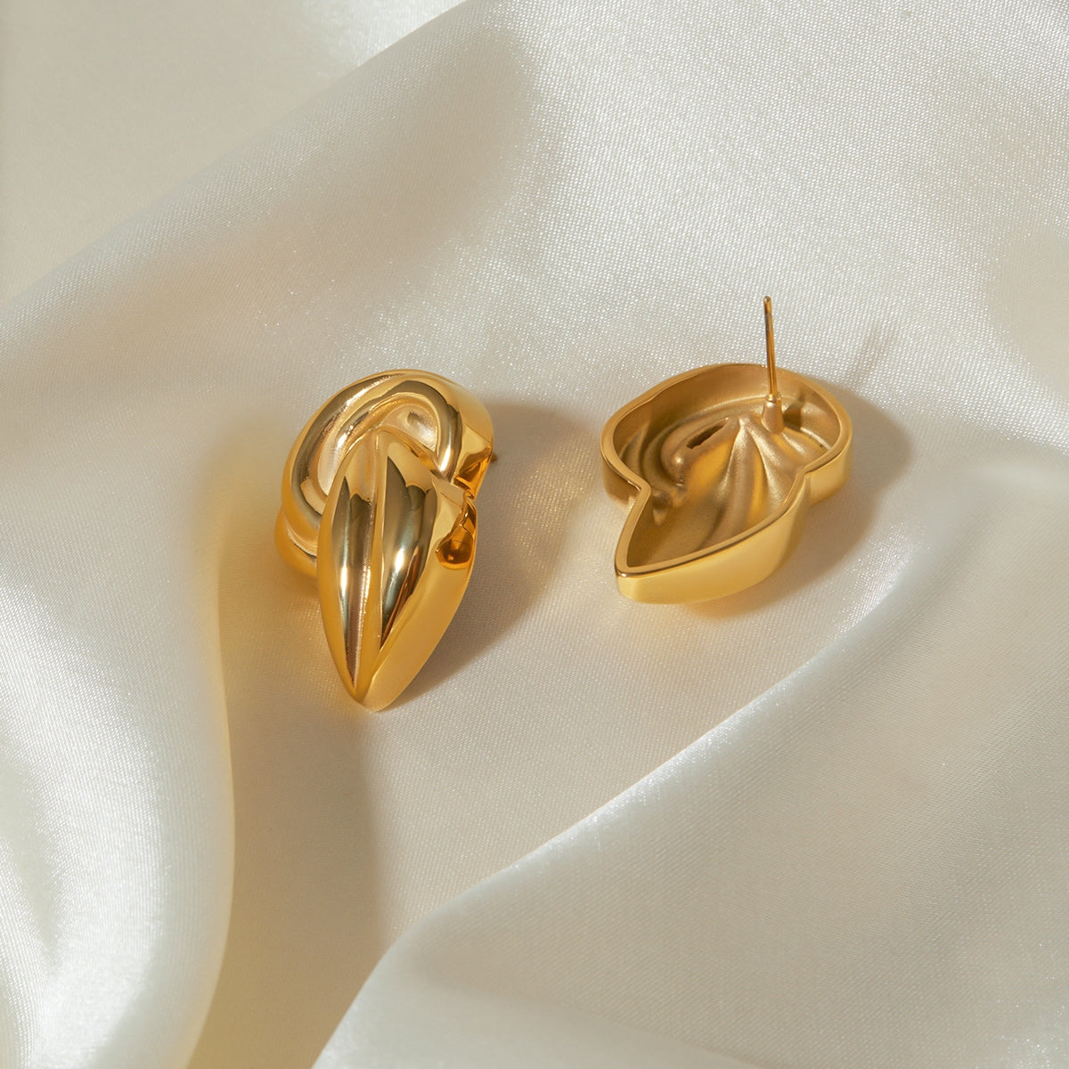 "A close-up view of earring an 18K Gold-Plated Stud Earrings. The earring features an intricate design with a twisted knot shape, adding a bold and elegant touch to the overall appearance."